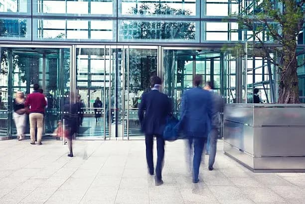 Business professionals entering a modern glass office building.